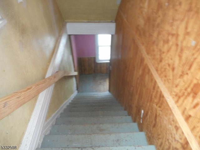 staircase featuring wooden walls