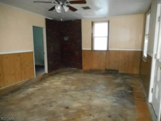 unfurnished room with ceiling fan, wooden walls, and concrete floors