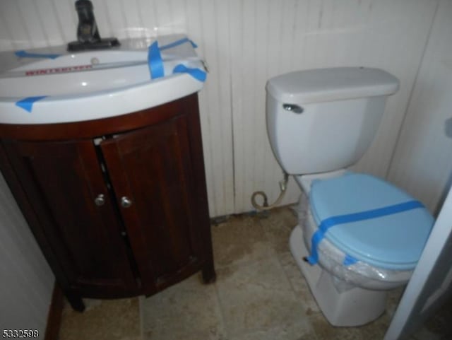 bathroom featuring wooden walls, vanity, and toilet