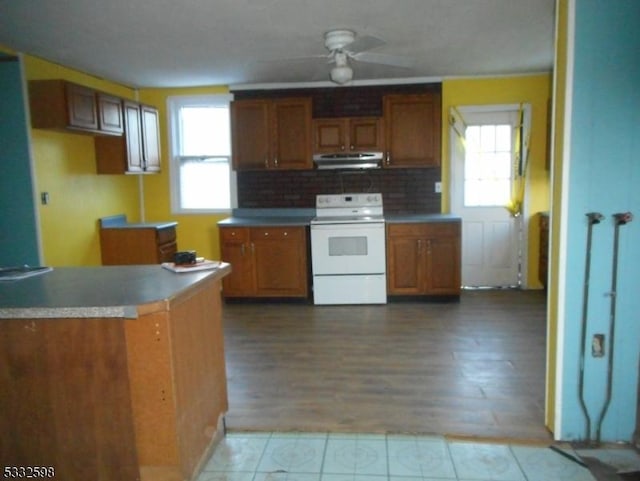 kitchen featuring ceiling fan, light hardwood / wood-style floors, backsplash, and electric range