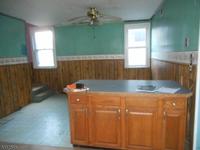 kitchen featuring wooden walls, ceiling fan, and light tile patterned floors