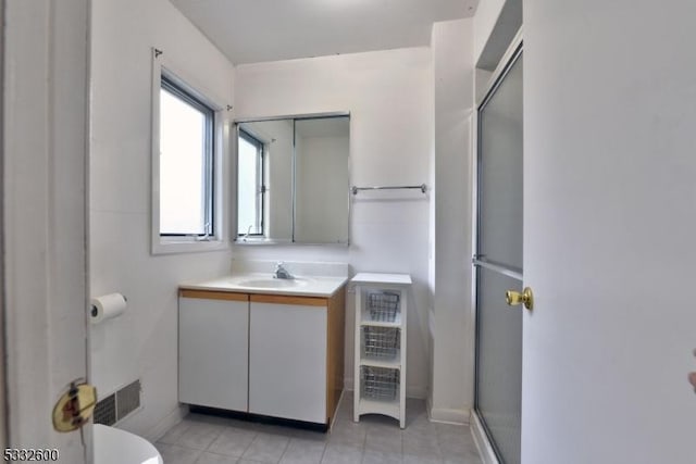 bathroom featuring toilet, tile patterned flooring, a shower with door, and vanity