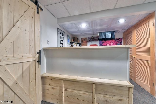 interior space featuring a barn door, light brown cabinetry, and a paneled ceiling