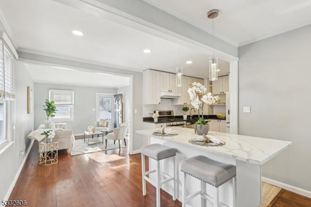 kitchen with pendant lighting, a breakfast bar, white cabinetry, dark hardwood / wood-style flooring, and stainless steel range with gas cooktop