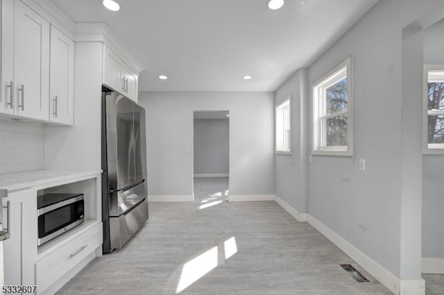 kitchen with light wood-type flooring, white cabinetry, recessed lighting, appliances with stainless steel finishes, and baseboards