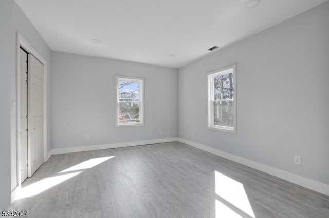 unfurnished bedroom featuring wood finished floors, visible vents, and baseboards