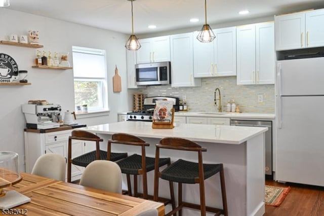 kitchen featuring appliances with stainless steel finishes, white cabinetry, pendant lighting, and sink