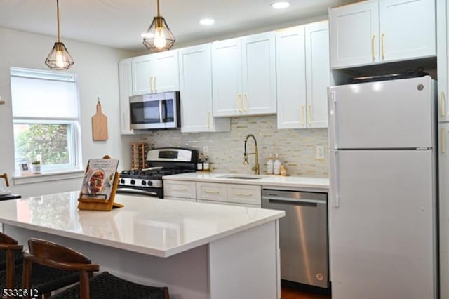 kitchen featuring white cabinets, appliances with stainless steel finishes, a center island, and sink