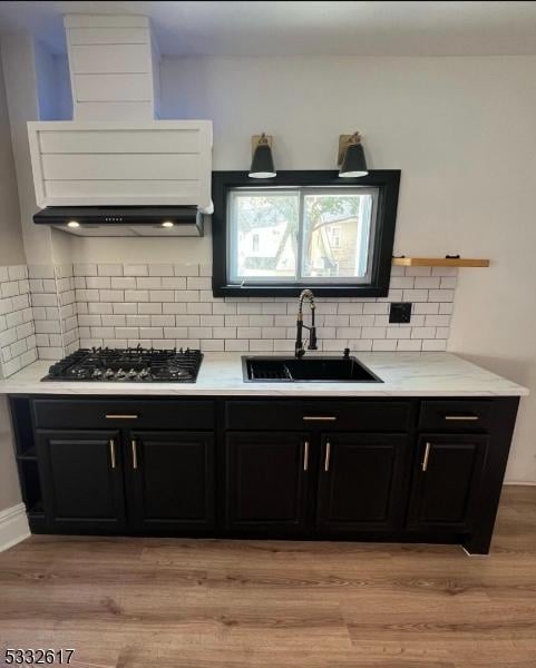 kitchen with sink, light hardwood / wood-style flooring, decorative backsplash, and black gas stovetop