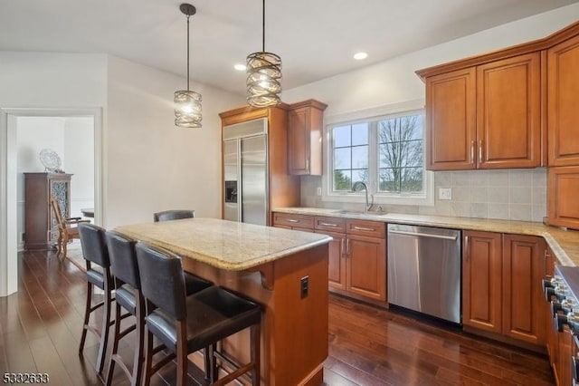 kitchen with a breakfast bar, sink, a center island, appliances with stainless steel finishes, and backsplash