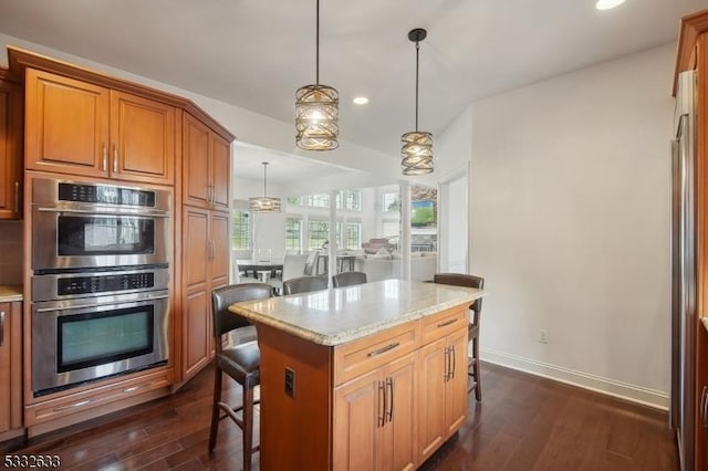 kitchen with a kitchen island, pendant lighting, a kitchen breakfast bar, stainless steel appliances, and light stone countertops