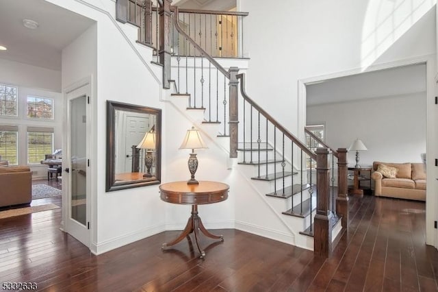 stairway with hardwood / wood-style floors and a towering ceiling