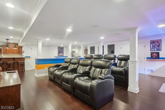 cinema room featuring ornate columns, crown molding, and dark hardwood / wood-style flooring