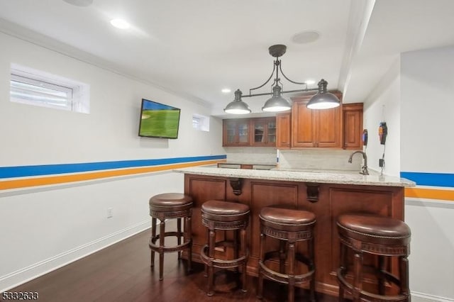 bar featuring crown molding, dark hardwood / wood-style floors, light stone counters, and decorative light fixtures