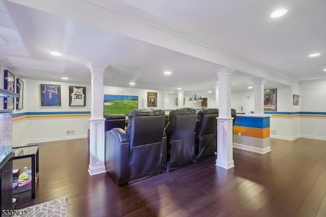 home theater featuring dark wood-type flooring, crown molding, and decorative columns