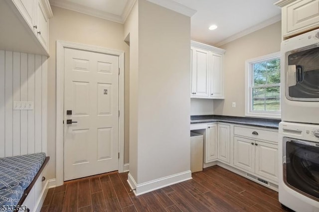 kitchen with stacked washing maching and dryer, ornamental molding, and white cabinets