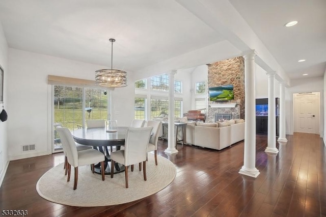 dining space with ornate columns, dark hardwood / wood-style floors, and a fireplace