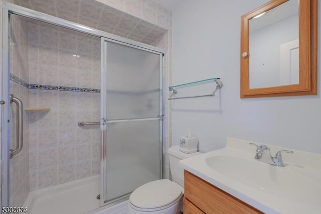 bathroom with toilet, a shower with door, and vanity