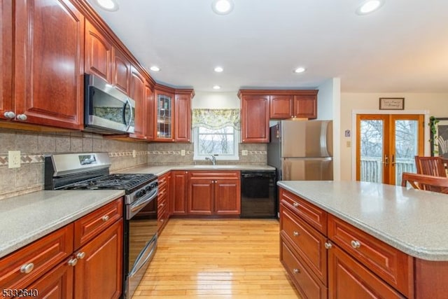 kitchen with french doors, sink, tasteful backsplash, light hardwood / wood-style floors, and stainless steel appliances