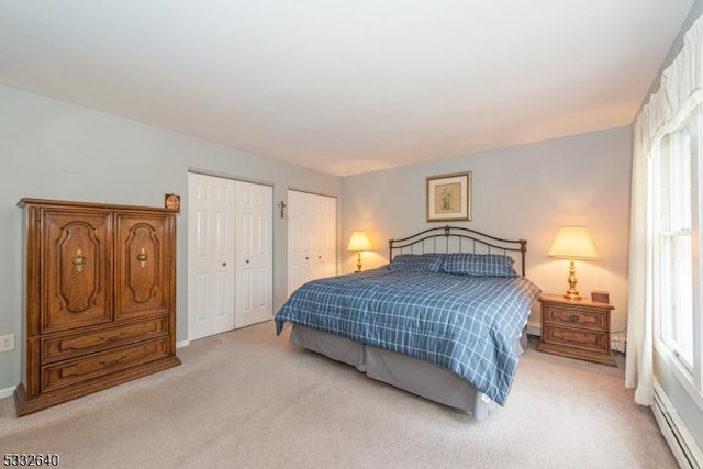 carpeted bedroom featuring a baseboard heating unit and multiple closets