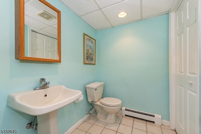 bathroom featuring tile patterned floors, a drop ceiling, a baseboard heating unit, sink, and toilet