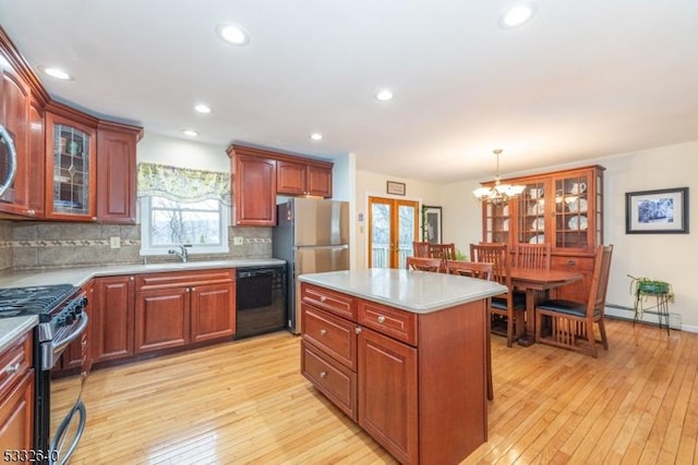 kitchen featuring stainless steel appliances, light hardwood / wood-style flooring, a notable chandelier, decorative light fixtures, and a kitchen island