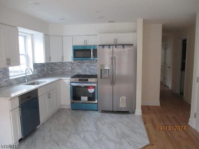 kitchen with backsplash, white cabinetry, sink, and stainless steel appliances