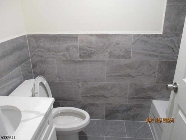 bathroom with tile patterned floors, vanity, toilet, and a washtub