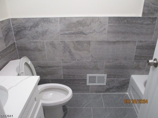 bathroom featuring a washtub, tile patterned floors, vanity, and toilet