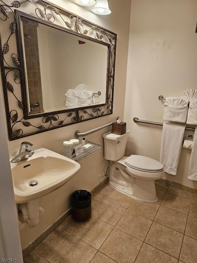 bathroom with toilet, tile patterned floors, and sink