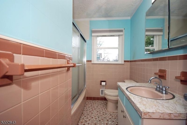 full bathroom with tile patterned floors, vanity, tile walls, enclosed tub / shower combo, and toilet