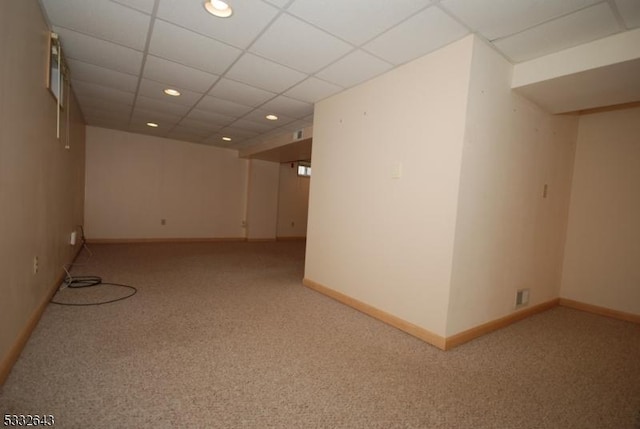 spare room with a paneled ceiling and light colored carpet