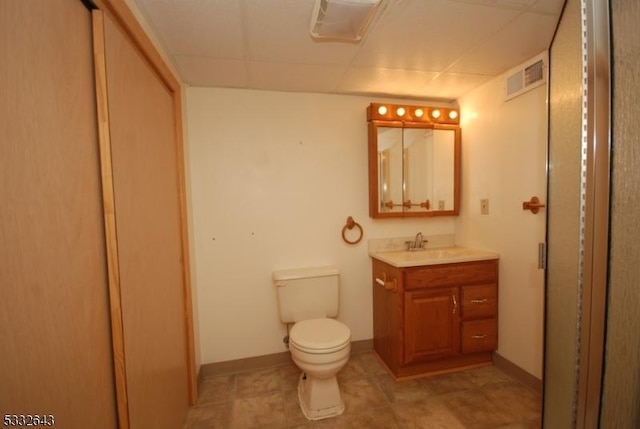 bathroom with a paneled ceiling, vanity, and toilet