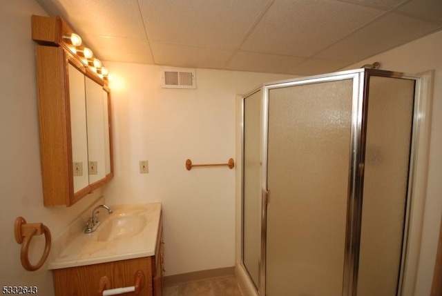 bathroom featuring vanity, a drop ceiling, and a shower with door