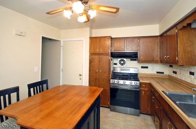 kitchen featuring butcher block countertops, ceiling fan, sink, and stainless steel gas range