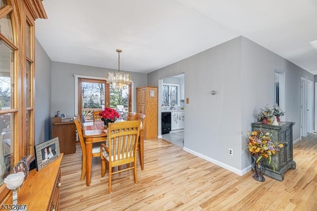 dining area with light hardwood / wood-style floors and a notable chandelier