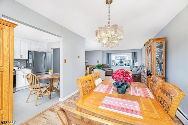 dining space with baseboard heating, light wood-type flooring, and a notable chandelier