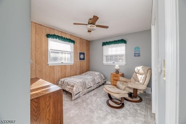 carpeted bedroom with a baseboard radiator, wood walls, and ceiling fan