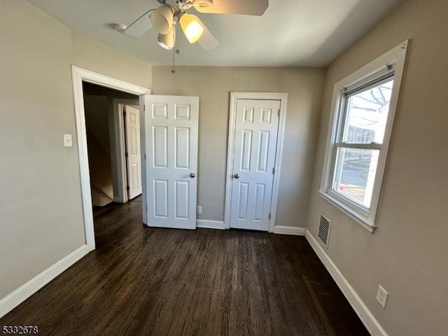 unfurnished bedroom featuring ceiling fan, a closet, and dark wood-type flooring