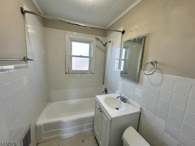 bathroom featuring vanity, crown molding, tile patterned flooring, tiled shower / bath combo, and tile walls