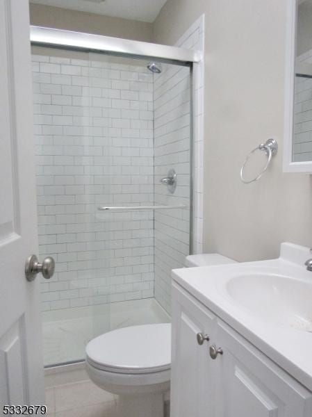 bathroom featuring tile patterned flooring, vanity, toilet, and a shower with shower door