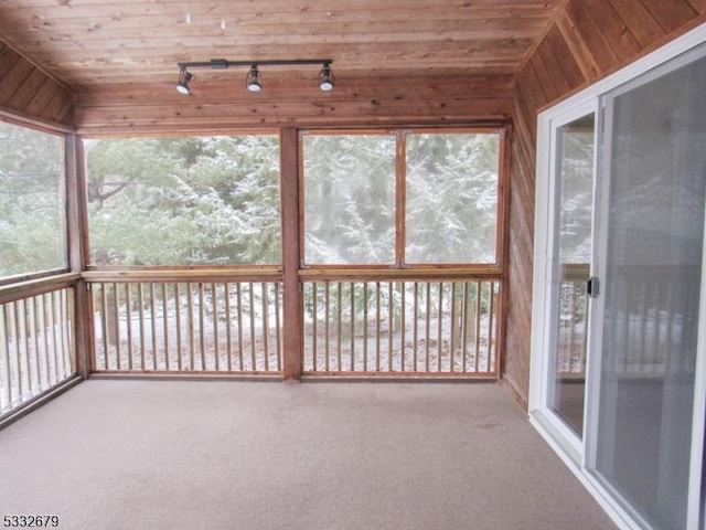 unfurnished sunroom featuring wooden ceiling and rail lighting