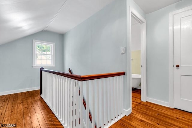 corridor with lofted ceiling and hardwood / wood-style floors