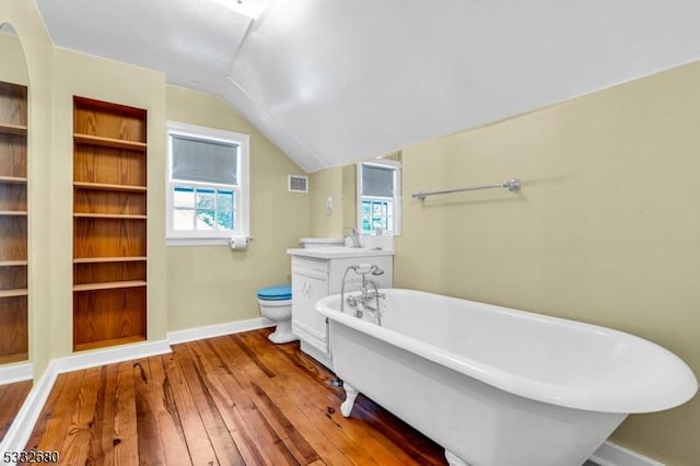 bathroom with toilet, hardwood / wood-style flooring, a bath, vaulted ceiling, and built in shelves