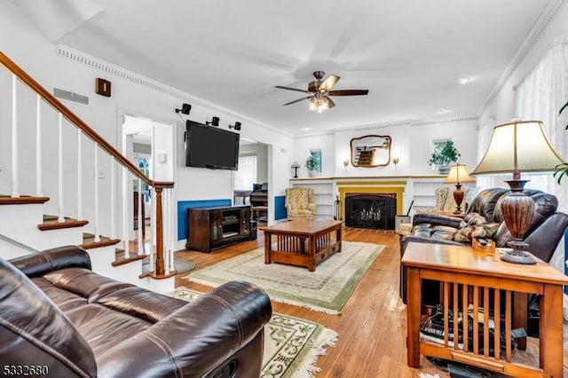 living room with light wood-type flooring, ceiling fan, crown molding, and plenty of natural light