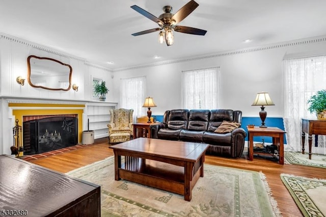 living room with ceiling fan, crown molding, a fireplace, and hardwood / wood-style floors