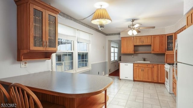 kitchen with white appliances, decorative backsplash, sink, kitchen peninsula, and ceiling fan