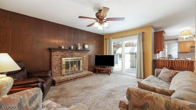 living room with ceiling fan, a brick fireplace, wood walls, and light colored carpet