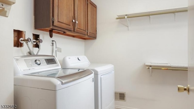 clothes washing area with cabinets and washing machine and clothes dryer