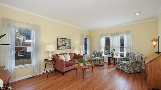 living area featuring ornamental molding, wood finished floors, visible vents, and a healthy amount of sunlight